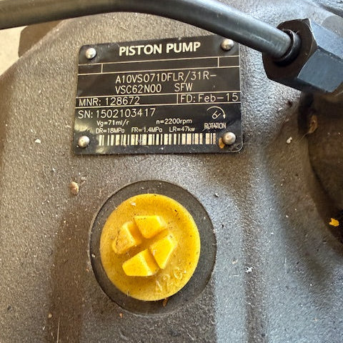 Close-up of a piston pump with a yellow cap and label on a beige background