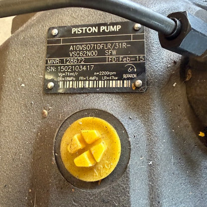 Close-up of a piston pump with a yellow cap and label on a beige background